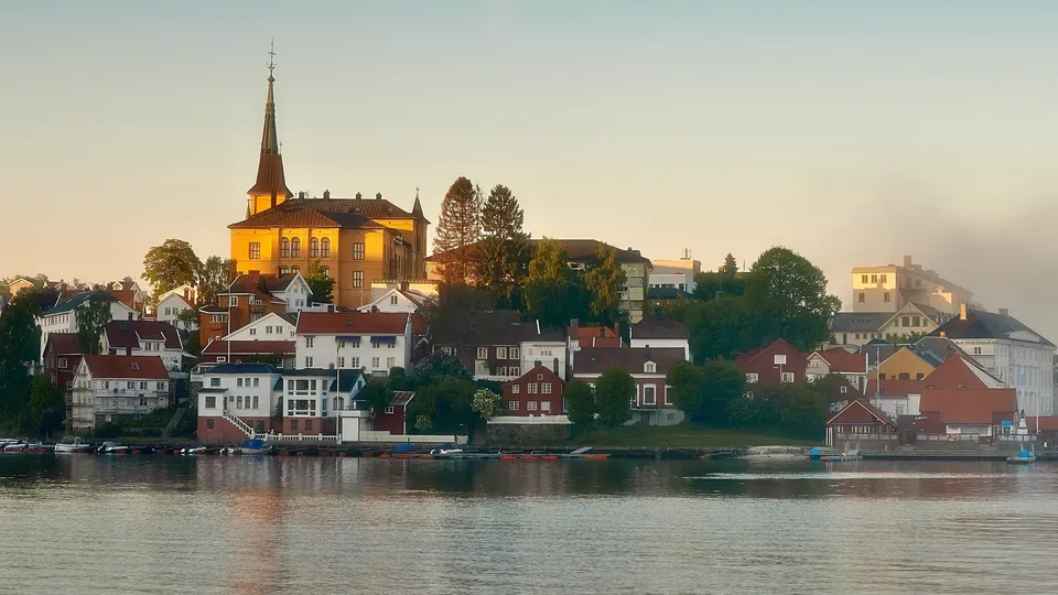 Varmepumpe i Arendal: Vannkantby med gul kirke og fargerike bygninger langs elven.