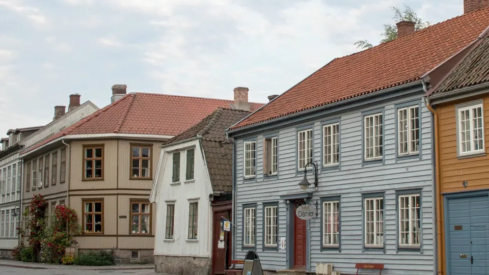 Varmepumpe Fredrikstad: Rekke med fargerike historiske trehus med røde takstein.
