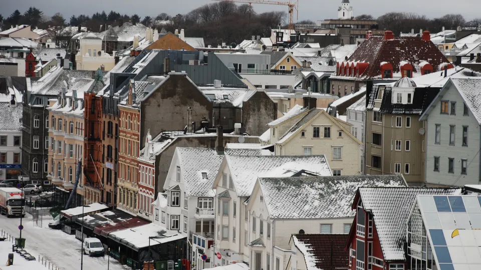 Snødekt europeisk by med fargerike bygninger og kirketårn.