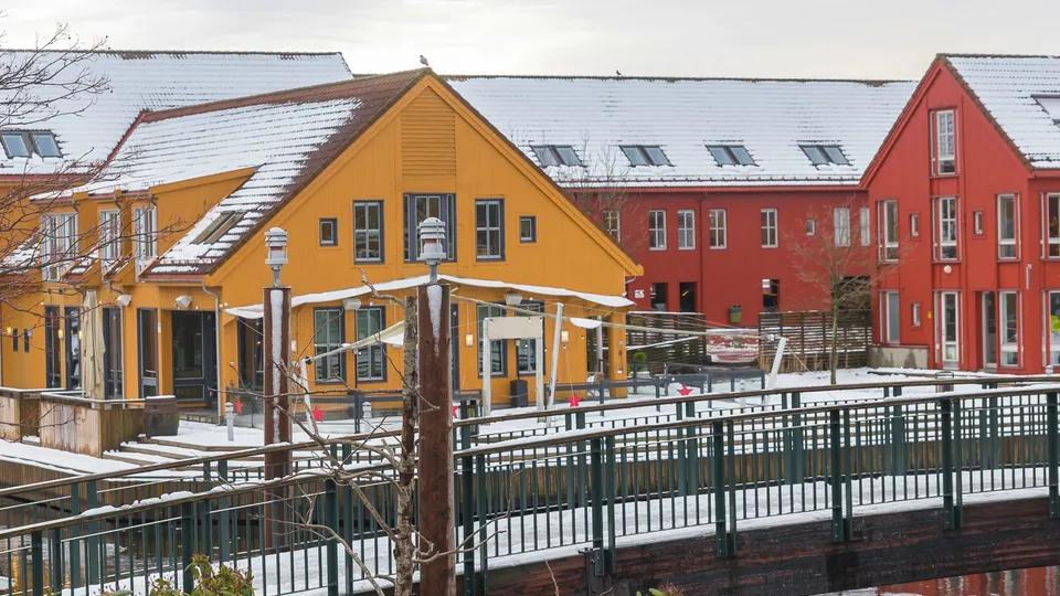 Varmepumpe Kristiandsand. Fargerike bygninger og bru som er dekket i snø