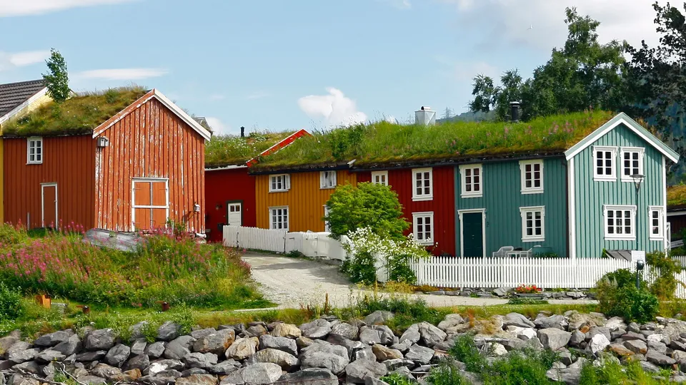 Fargerike trehus med torvtak ved steinete strand i Mo i Rana.