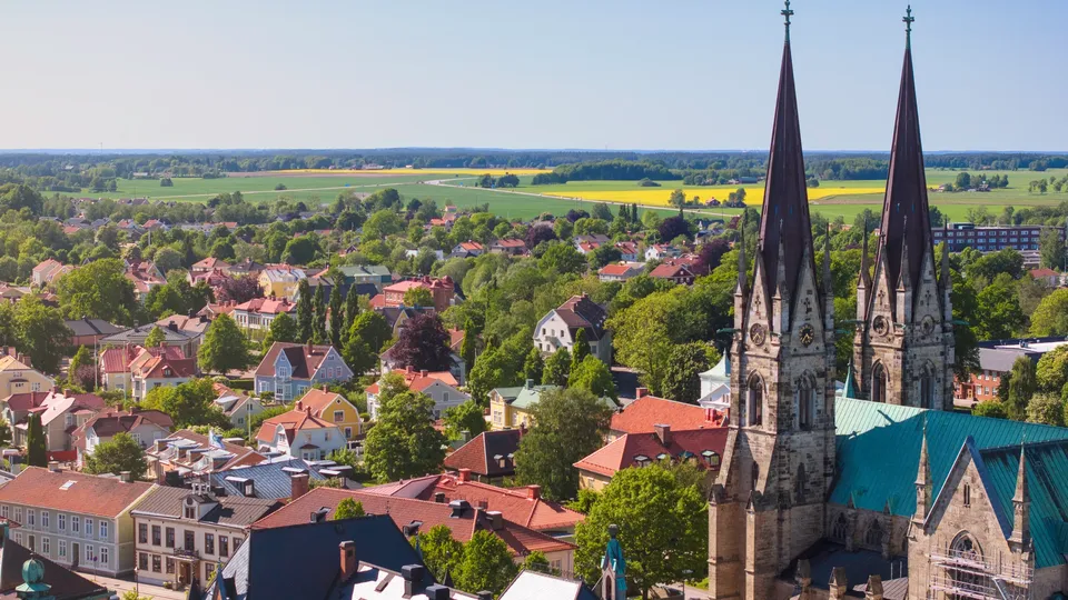 Kyrka med två torn överblickar Skara med jordbruksmark i bakgrunden.