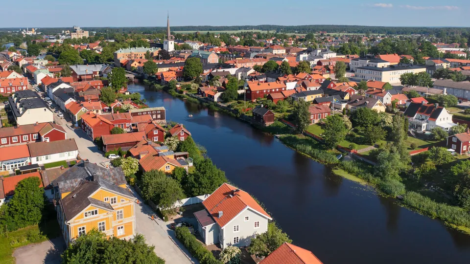 Flygvy över Arboga med röda hus längs en å och kyrktorn.