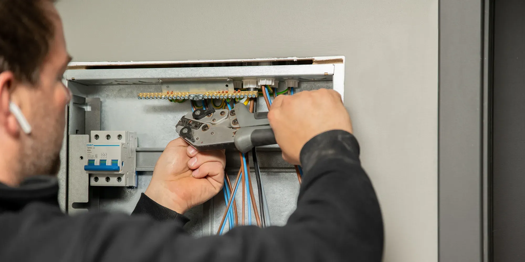 Elektriker installerer ledninger i strømbryterpanel.