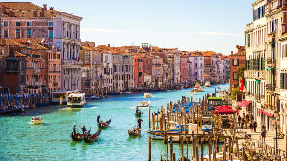 Gondole e barche sul Canal Grande di Venezia con edifici storici lungo la via d'acqua.