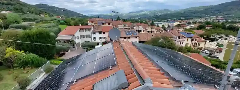 Pannelli solari installati su un tetto in coppi che si affaccia su un quartiere residenziale con colline verdi sullo sfondo.