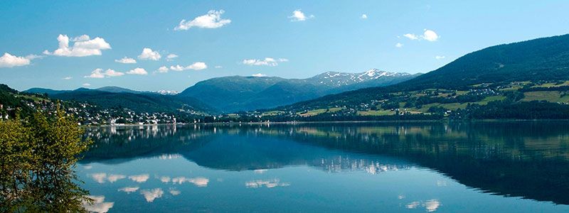 Et solfylt landskapsbilde utover et vann med fjell i bakgrunnen