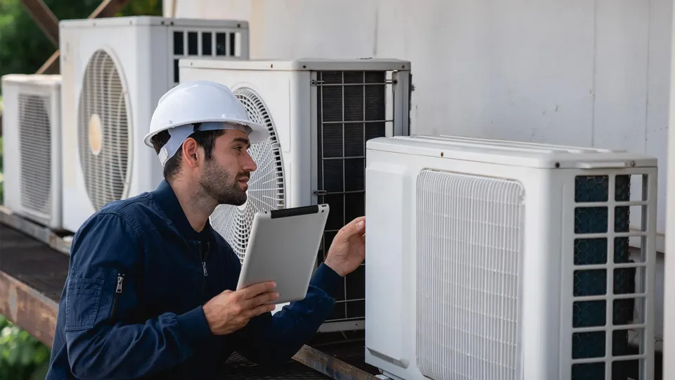 Installatør inspicerer klimaanlæg med tablet.