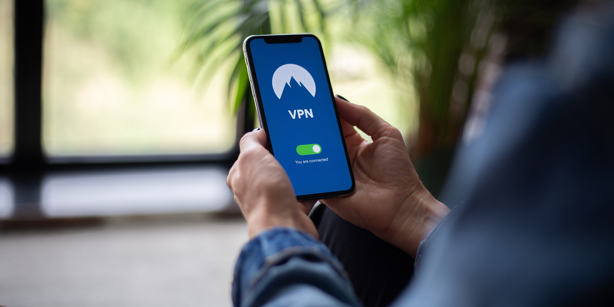 Bilde av en person som holder en mobil i hånda hvor VPN er skrudd på.