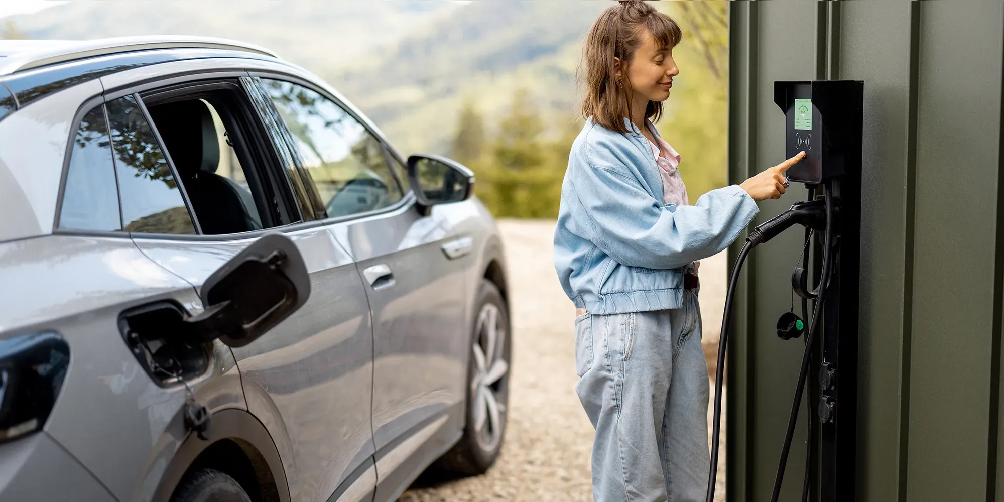 Frau lädt Elektrofahrzeug an heimischer Ladestation.