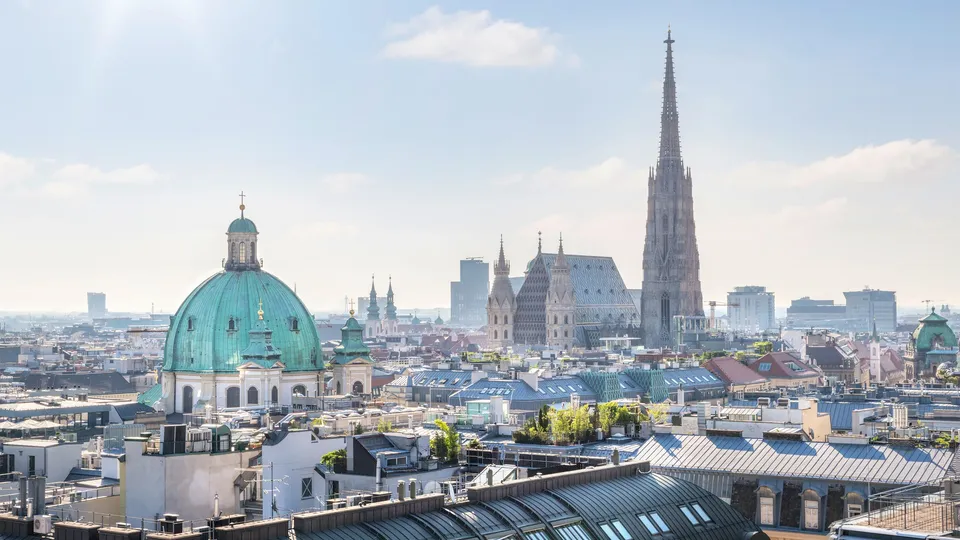Wiener Stadtansicht mit Stephansdom-Spitze und türkisfarbener Kuppelkirche.