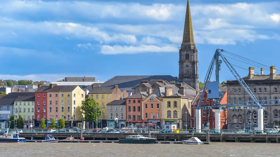 Waterford city quayside with colourful buildings, church spire and boats along the River Suir