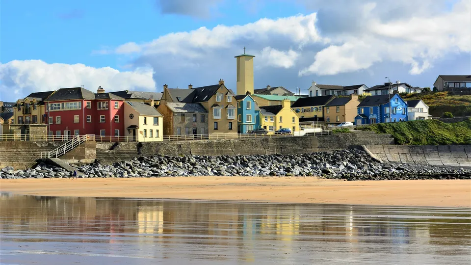 County Wexford: Colorful waterfront houses reflected in wet sand at a beach.