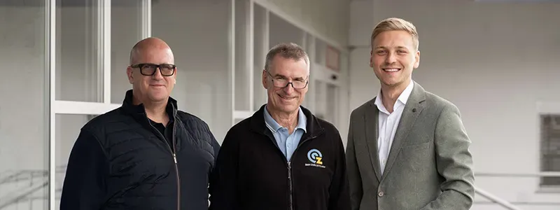 Zach Solutions GmbH – drei Geschäftsführer im Gebäudeflur, einer trägt Jacke mit Firmenlogo